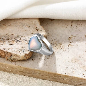 Vue détaillée d'une bague coeur en pierre de lune argentée sur surface en pierre