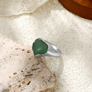 Détail d'une bague coeur argentée avec gemme verte sur une base en pierre naturelle