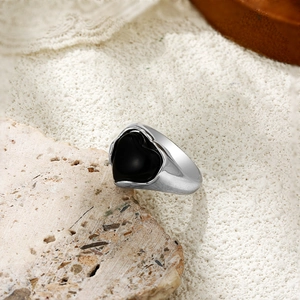 Vue détaillée d'une bague coeur en argent avec pierre noire sur dentelle et fond de pierre
