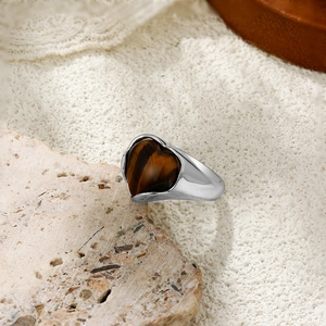 Détail d'un œil de tigre en forme de cœur serti sur une bague large argentée sur pierre