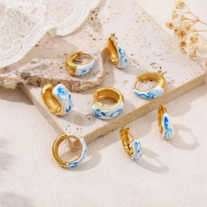 Detail of 18K gold-plated C-hoop earrings with blue and white enamel marble patterns