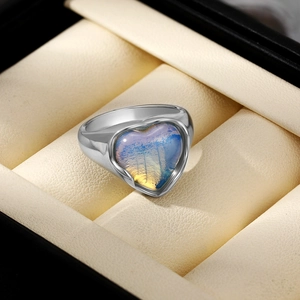 Vue macro d'une bague coeur en argent avec opale iridescente dans un coffret à bijoux