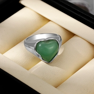 Gros plan d'une bague en argent avec pierre précieuse verte en forme de cœur en écrin