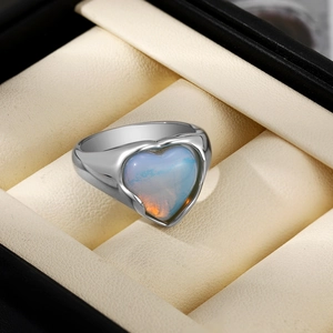 Gros plan d'une bague avec opale en forme de cœur et anneau argenté dans un écrin