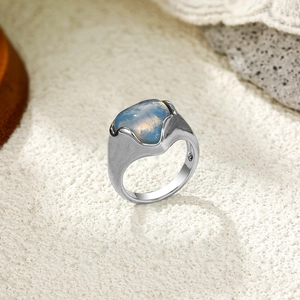 Détail d'une bague large argentée avec finition texturée et pierre de lune bleue