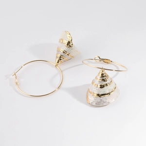 Detail of gold hoop earrings featuring textured white conch shell pendants on a plain background