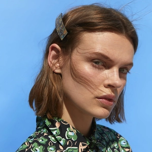 Classic abalone texture barrette in blue resin shown on a woman's brown hair
