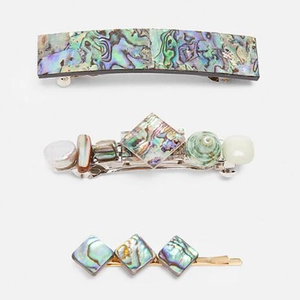 Detailed view of three resin hair clips with iridescent abalone shell textures
