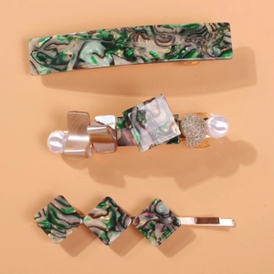 Detail of three retro hair clips featuring green abalone texture, pearls, and shell charms