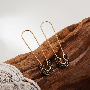 Macro detail of gold-plated safety pin earrings with micro-pave black cubic zirconia stones