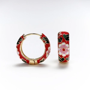 Detail of red enamel hoop earrings featuring floral patterns and gold metal base