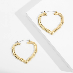 Detail of 14K gold bamboo-textured heart hoop earrings on minimalist display blocks