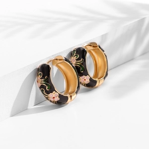 Detail of vintage enamel hoop earrings with pink flower patterns and golden interior