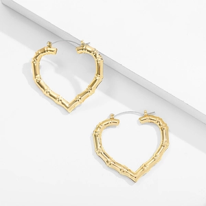 Detailed view of 14K gold bamboo-textured heart hoop earrings on white steps