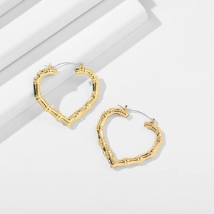 Detailed view of 14K gold heart hoop earrings with bamboo texture on white background