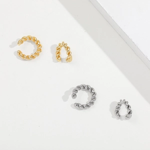 Detailed macro view of gold and silver twisted cable ear cuffs in a minimalist design