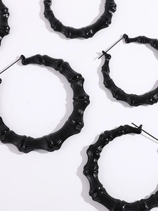 Detail of black hoop earrings featuring a distinct bamboo texture and glossy finish