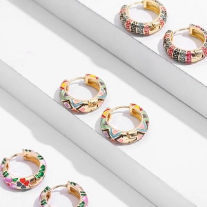Detail of colorful enamel hoop earrings with floral and geometric patterns on gold metal