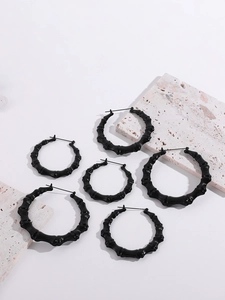 Three pairs of black bamboo-style heart hoop earrings in varying sizes on stone