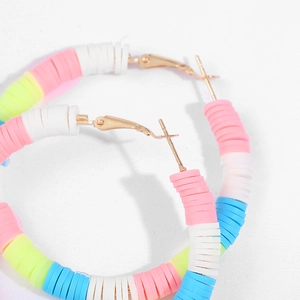 Macro detail of Bohemian colorful heishi bead hoop earrings with golden metal clasps