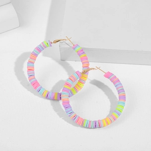 Macro view of colorful macaron heishi beads on bohemian style gold hoop earrings