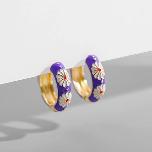 Detail of purple enamel hoop earrings with white daisy patterns and gold plating