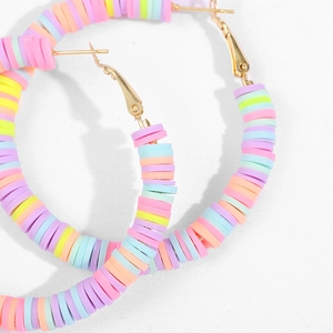 Macro shot of colorful polymer clay beads on gold hoop earrings with beach style