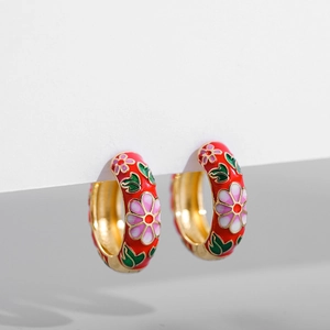 Detail of vintage gold-tone hoop earrings with red floral enamel and green leaves