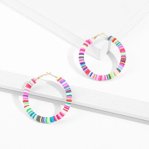 Close-up of colorful bohemian C-shaped earrings with Heishi beads on white stand