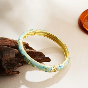 Macro detail of vintage cloisonné enamel bangle with floral patterns on wood base