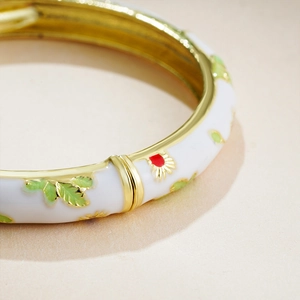 Detailed close-up of 14K gold enamel bracelet with floral pattern and spring clasp