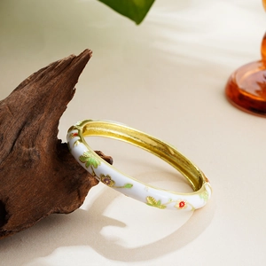 Detail of 14K gold enamel flower bracelet featuring colorful floral patterns on dark wood