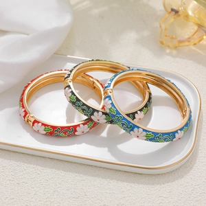 14K gold enamel flower bangles in red, black and blue colors set on ceramic plate