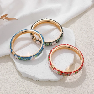 Detailed view of 14K gold plated enamel floral bangles in blue, black, and red colors