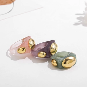 Detailed view of colorful chunky resin rings with inlaid gold geometric metal accents