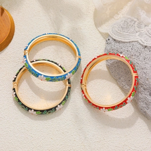 Detailed view of three vintage enamel flower bangles with gold-plated floral patterns