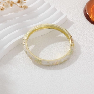 Macro detail of French vintage style enamel flower bracelet with gold plating on white stand