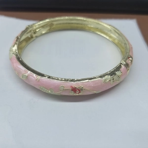 Detail of pink enamel bangle with golden leaves and red flower relief craftsmanship