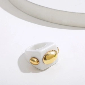 Detail view of a white resin wide band ring with a polished gold oval metal accent