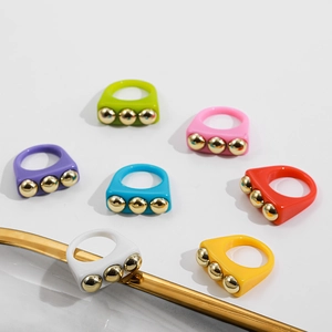 Detailed top view of colorful resin rings with triple gold stud accents in candy colors