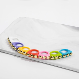 Macro view of colorful Y2K resin rings with gold stud accents on marble tray