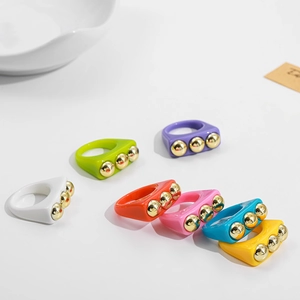 Detailed view of colorful resin Y2K rings with golden metal bead studs in seven vibrant colors