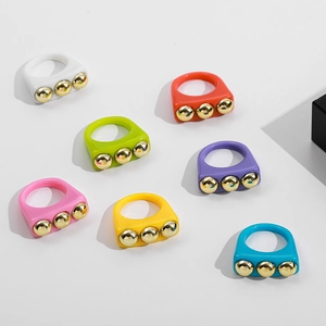 Flat lay of colorful Y2K resin rings featuring gold metal studs on a white background