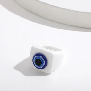 Macro view of white resin square ring featuring a blue evil eye design with silver glitter