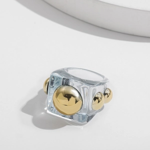 Macro detail of geometric resin ring with gold metal spheres and clear finish