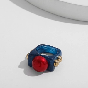 Close-up of blue marble resin ring with red center stone and gold metal stud accents