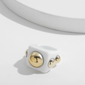 Close-up of a white resin square ring with embedded golden metallic studs for women
