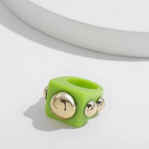 Detail of green resin ring with gold metal studs featuring a bold square Y2K design