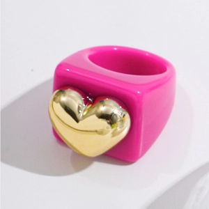 Detail of rose pink resin ring featuring a metallic gold heart accent in Y2K fashion style