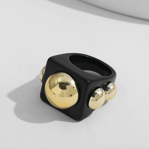 Macro detail of Y2K resin ring with black glossy finish and gold metallic spheres
